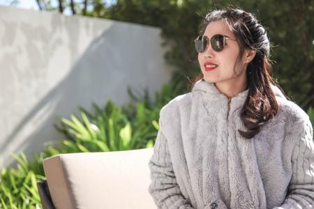 Woman Wearing Gray Fur Coat and Sunglasses Sitting Near Green Leaf Plants