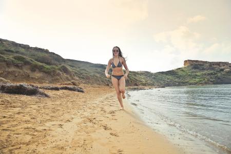 Woman Wearing Grey Bikini Running On White Sand Seashore