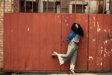 Woman Wearing Grey Jumpsuit Standing Beside Brown Metal Gate