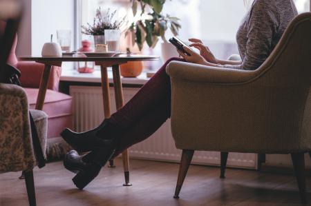Woman Wearing Heather Gray Long Sleeve Top Red Fitted Pants and Chunky Boots Sitting on Sofa