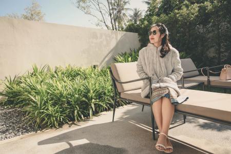 Woman Wearing Hoodie Sitting on Lounge Chair