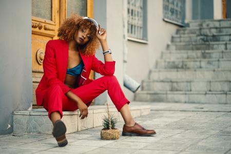 Woman Wearing Red Blazer and Pants Sitting on Marble Ground