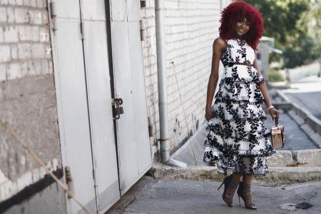 Woman Wearing White and Black Floral Sleeveless Dress Standing Beside White Painted Building