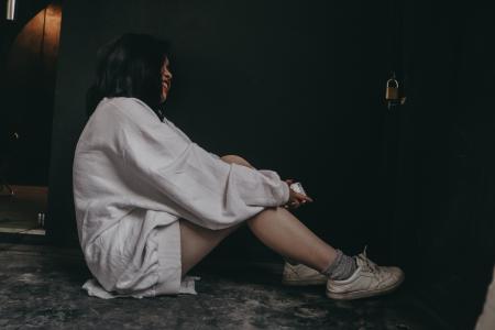 Woman Wearing White Dress Shirt and White Shoes Sitting on Black Flooring