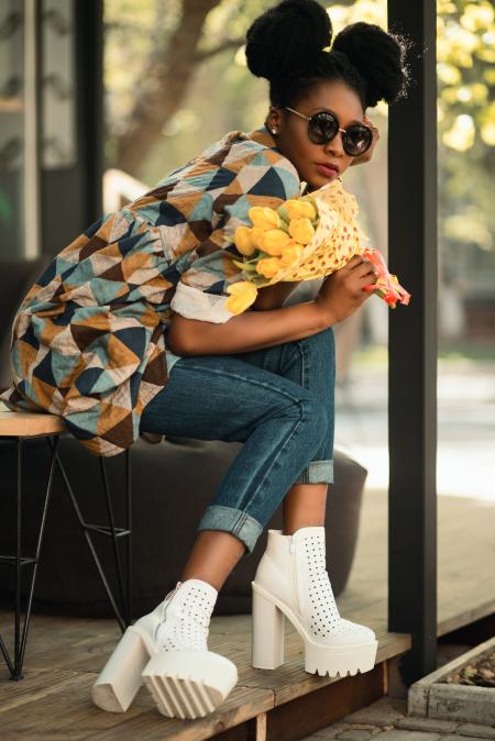 Woman Wearing White-green-yellow Geometric Sleeved Shirt, Blue Denim Pants and White Block Heeled Booties