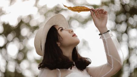 Woman Wearing White Long Sleeve Scoop-neck Top While Holding Brown Leaf