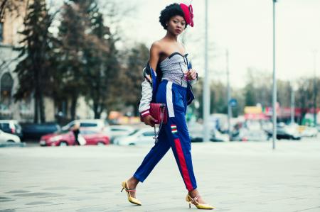 Woman Wearing White Sweetheart Neckline Shirt With Blue and Red Pants Walking Across the Street