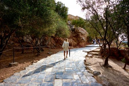 Woman Wearing White Top Holding Black Umbrella Walking On Cobblestone Pathway