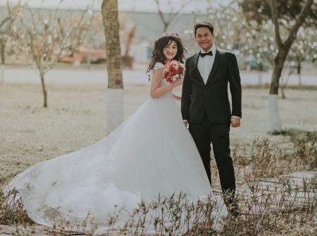 Woman Wearing White Wedding Ball Beside Man Wearing Black Notch-lapel Suit on Pathway Near the Green Grass Field