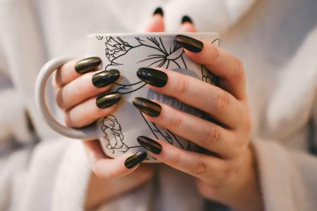 Woman With Black Manicure Holding White and Grey Floral Ceramic Cup