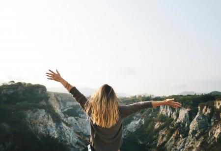 Woman With Blonde Hair at the Top of the Mountain Raising Her Hands