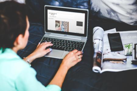 Woman with laptop lying down in bed