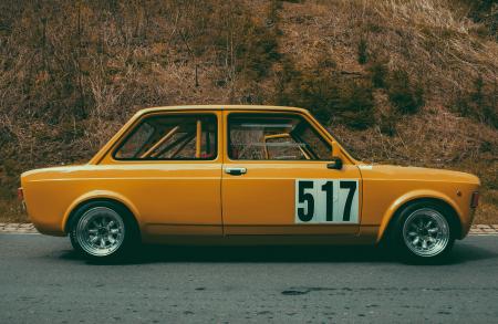 Yellow Sedan Beside Brown Leaf Plant during Daytime