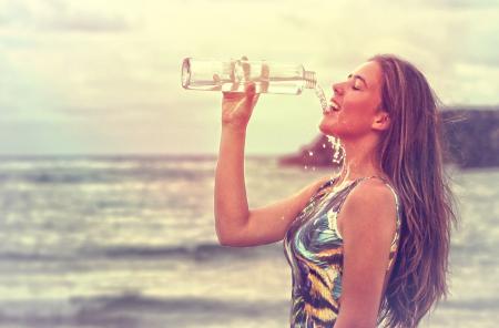 Young Woman Drinking Sparkling Water at the Beach - Health and Fitness