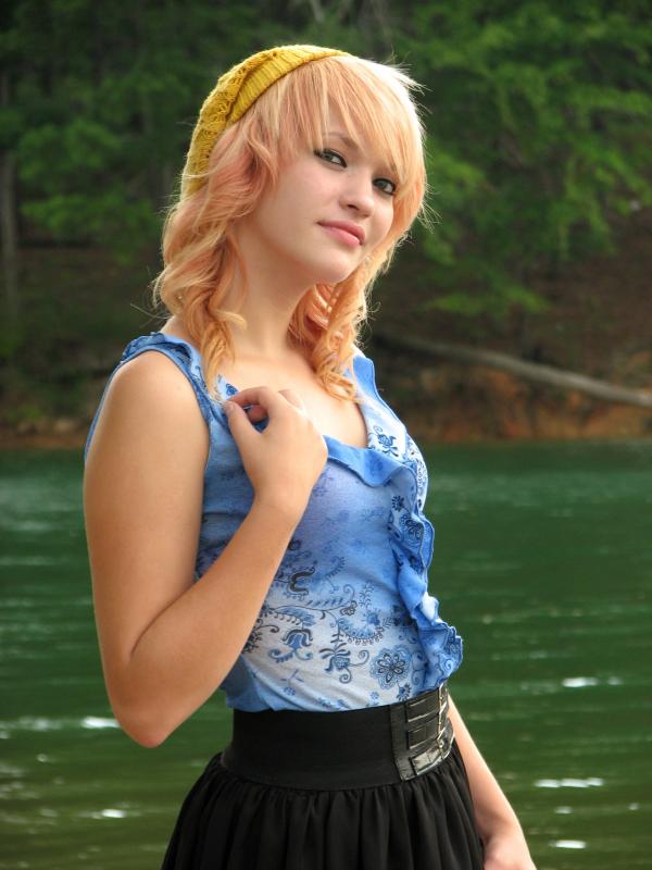 A beautiful young woman posing by a lake