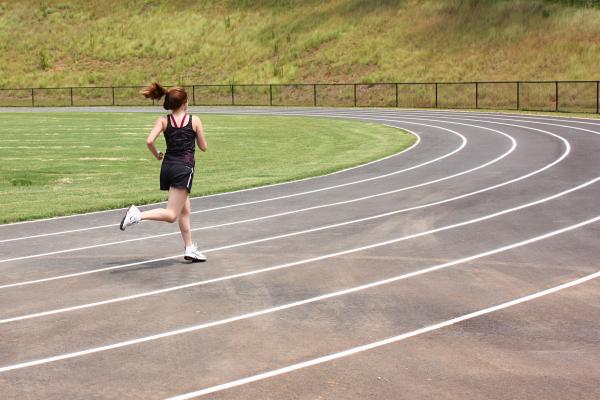A cute young girl running on a track