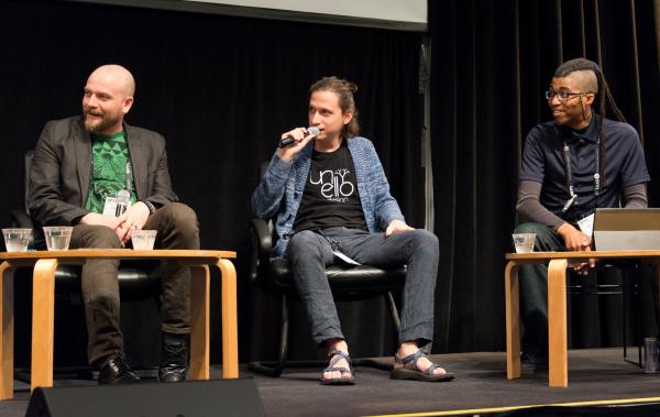 Aaron Lemke (Unello Design) discussing at indie dev panel at SVVR (full body view with Denny Unger of Cloudhead Games on left and Cymatic Bruce on right, all looking stage right)