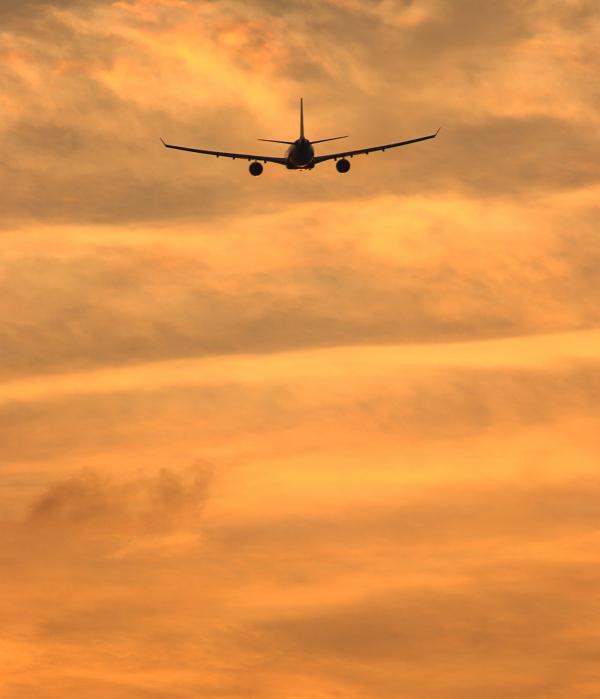 Airplane Flying To A Tropical Destination Into The Sunset