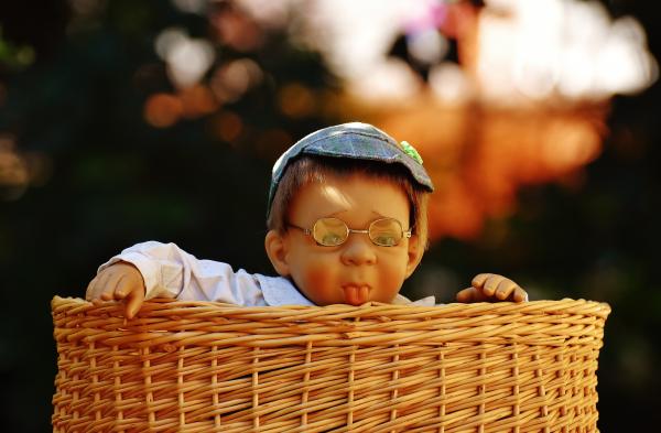 Baby Doll Wearing Eye Glasses Inside the Brown Wicker Basket