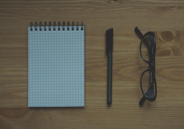 Black Framed Eyeglasses Near Graphing Paper Spiral Notebook