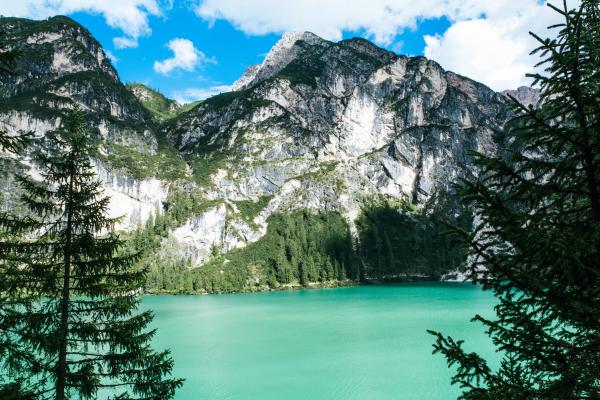 Black Mountain Near Green Body of Water Under Blue Sky