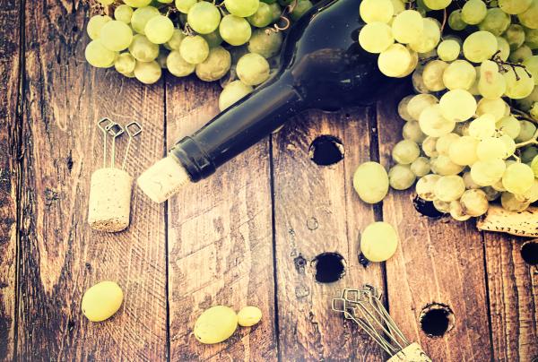 Bottle of wine with grape and corks on wooden table - Rustic looks