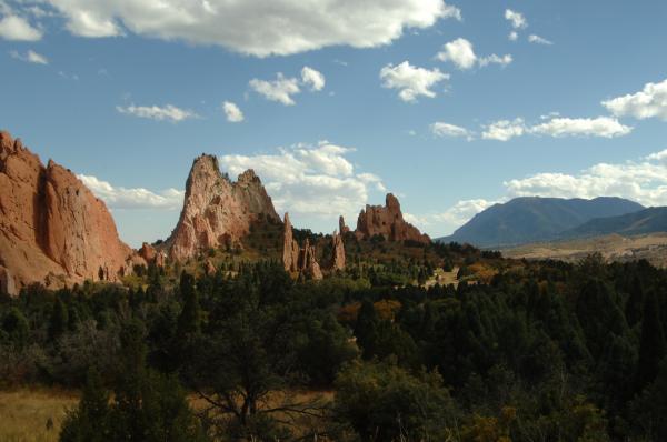 Brown Rock Formation Near Green Trees Under Cloudy Sky