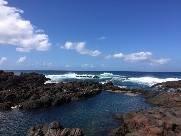 Brown Rocks Beside Ocean With Bubble Wave Under Blue Sky