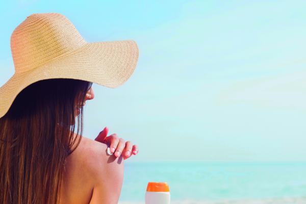 Brunette putting sunscreen on her shoulder