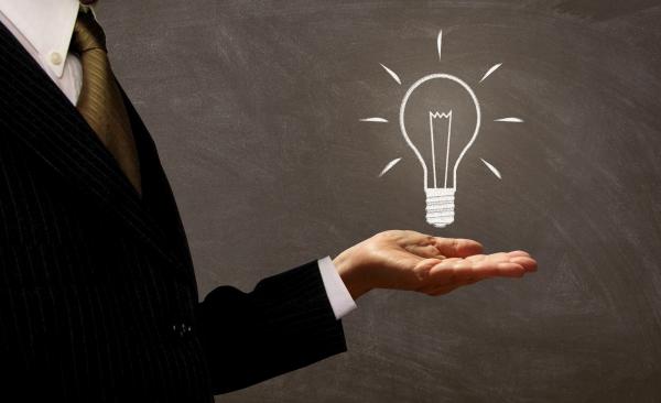 Businessman Holding Light Bulb on Chalkboard
