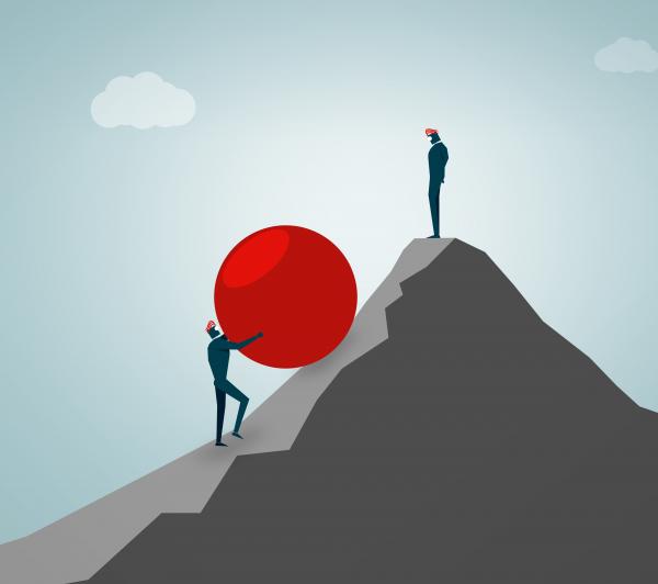 Businessman rolling huge ball up hill