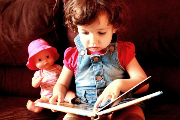 Child reading a book with doll