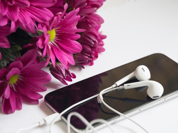 Close-Up Photography of Earphones on Top of Iphone 6 Near Flowers
