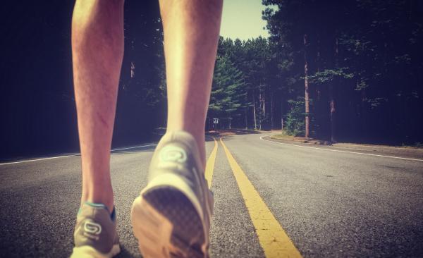 Feet of an athlete running on a deserted road
