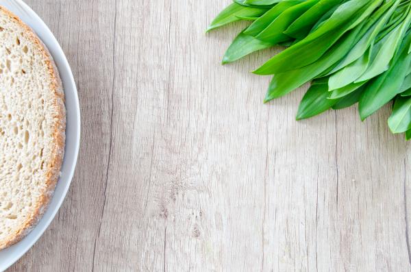 Fresh Garlic Leaves and Bread on Wooden Table