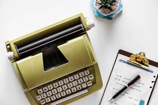 Gold Type Writer Beside Clip Board and Click Pen