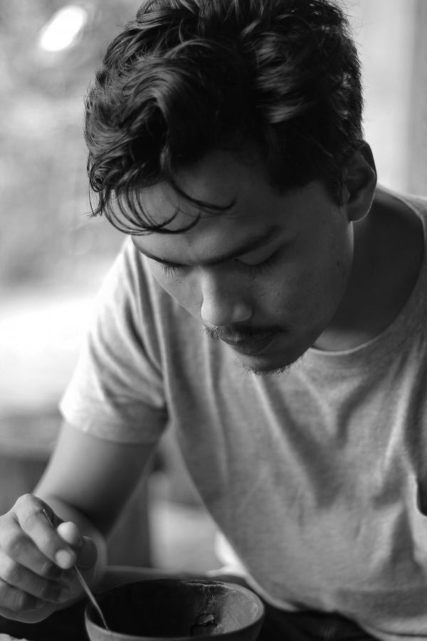 Gray Scale Photo of Man Holding Bowl and Spoon