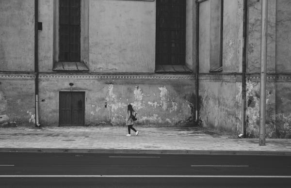 Gray Scale Photography of Woman Walking Near High Rise Building