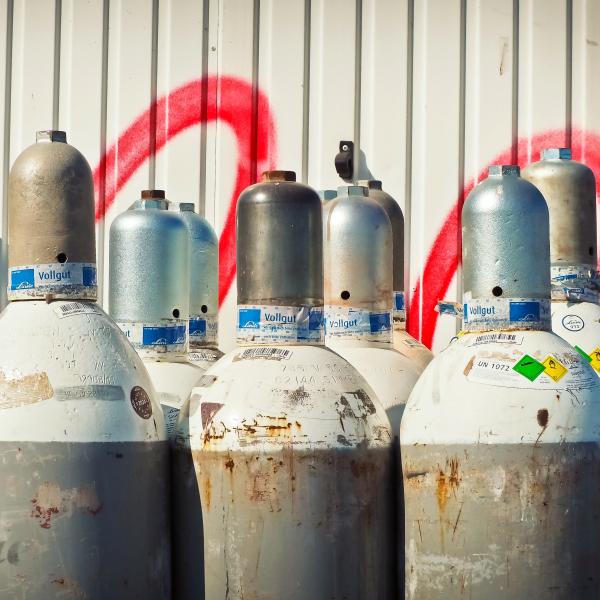 Gray Steel Gas Tanks Near White Steel Wall during Daytime