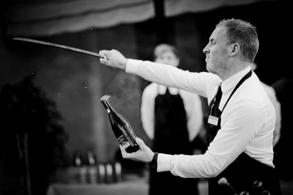Grayscale Of Man Holding Sword And Bottle