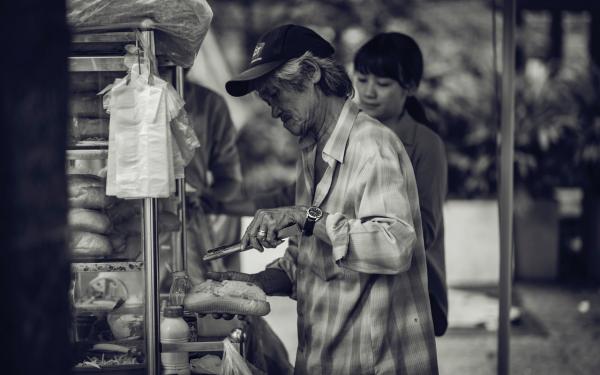 Grayscale Photo of a Man Selling Sandwiches on the Streets