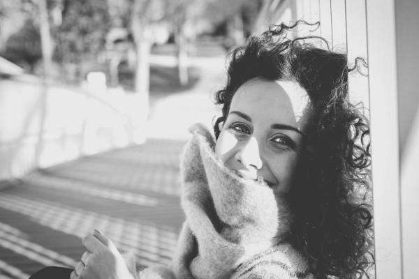 Grayscale Photo of Woman Leaning on White Pole