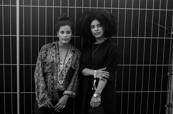 Greyscale Photo of 2 Woman Standing Behind Steel Bars