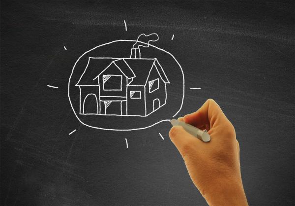 Hand drawing a house on blackboard - Real estate and housing concept