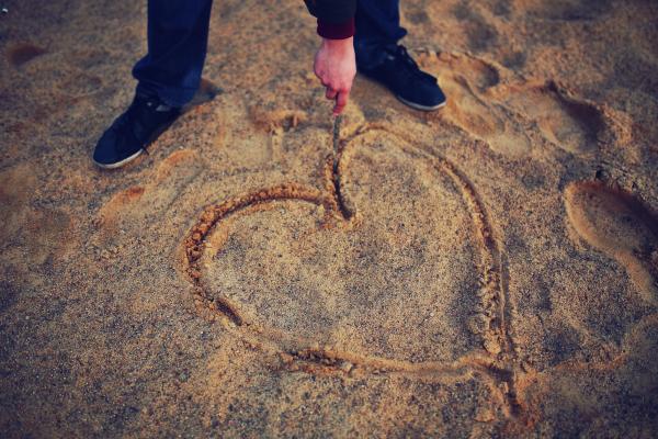 Hand drawing heart in the sand