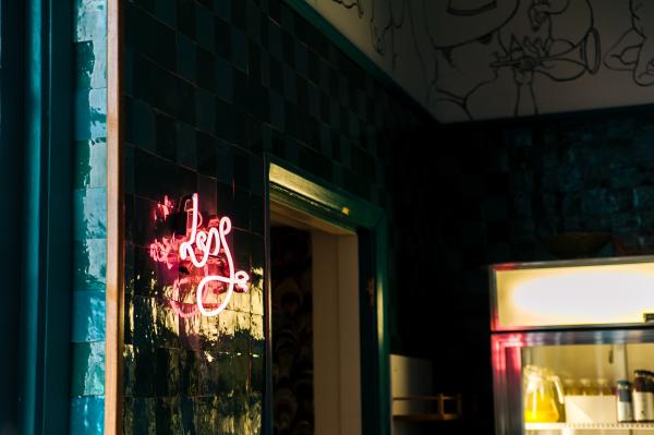 Less Neon Sign Mounted on Glass Board Near Open Window and Glass Display Rack