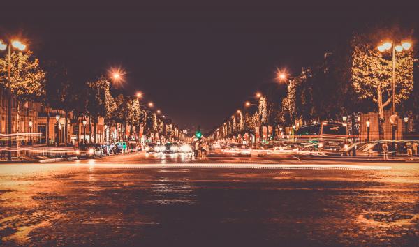 Lighted Street With Cars Passing by during Nighttime