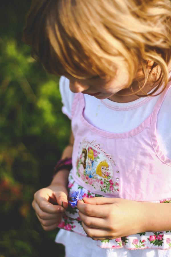 Little girl looks on flower