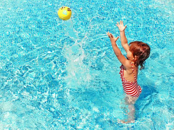 Little Girl Playing with a Ball in the Swimming Pool