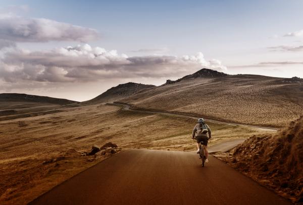 Lone Biker on the Road Through Mountains